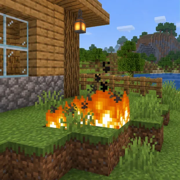 Two blocky grass fires burn close to a wooden house and fence in a green Overworld setting.