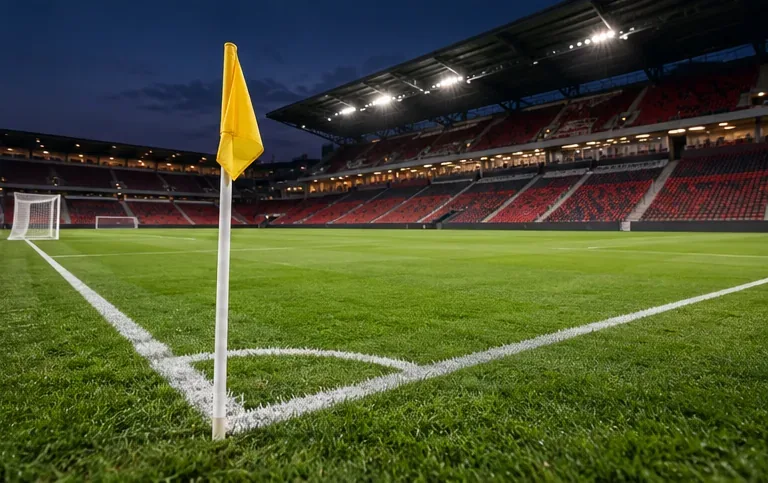 Gele hoekvlag op het kruispunt van twee witte lijnen op een voetbalveld in een stadion.