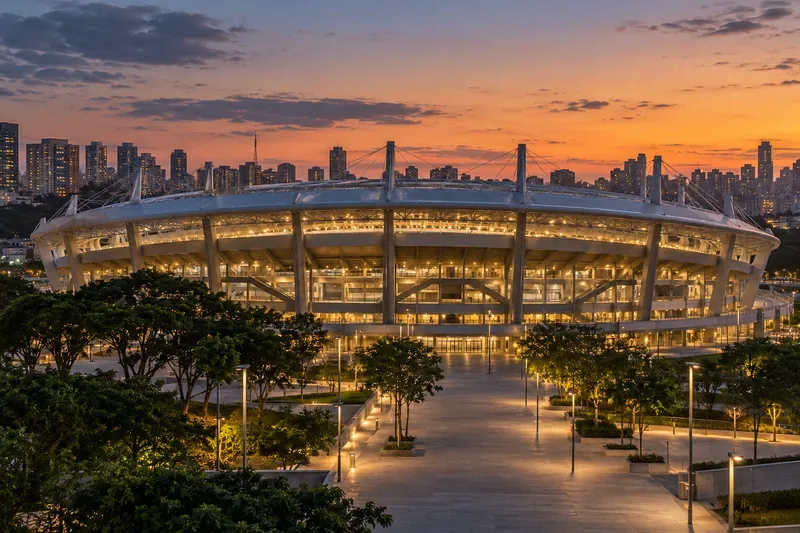 Een modern voetbalstadion en voetgangersplein bij zonsondergang.