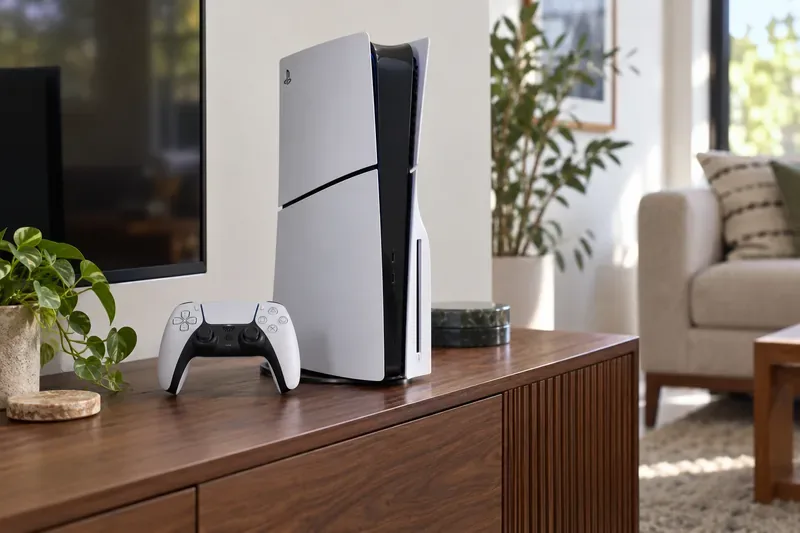 เครื่องเล่นเกม PlayStation 5 Slim พร้อมจอย DualSense วางอยู่บนตู้ไม้สำหรับเก็บอุปกรณ์มีเดีย