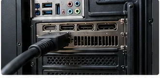 Close-up van een monitorkabel die is aangesloten op een van de onderste grafische kaartuitgangen aan de achterkant van een desktop-pc.