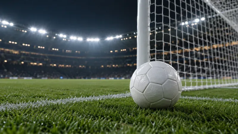 Een witte voetbal op het gras naast de doellijn, met daarachter het net en de stadionverlichting.