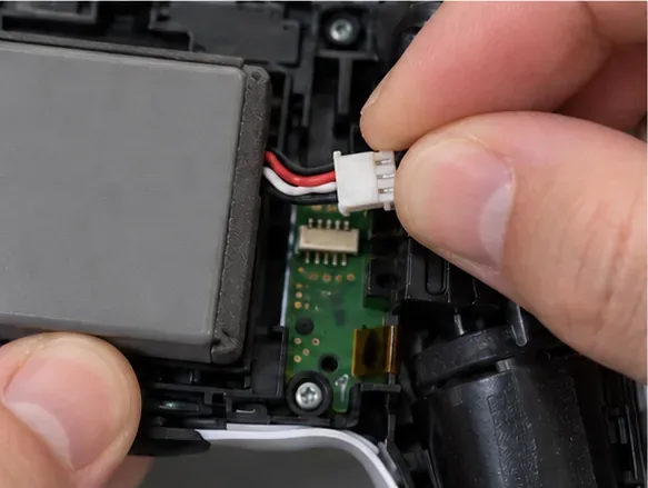 Com os dedos, segura o pequeno conector da bateria na placa-mãe para desconectá-lo sem puxar os fios.