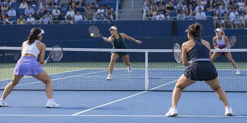 Vier vrouwen spelen een dubbelspelpunt rond het net op een blauwe hardcourtbaan.