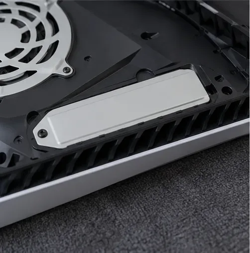 A tampa estreita que cobre o compartimento de expansão M.2 do PS5 fica visível no console aberto.