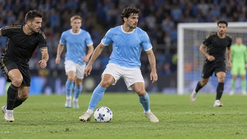 A midfielder in a sky-blue shirt controls the ball as opponents close in on a stadium pitch.