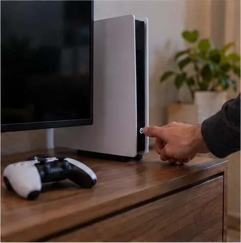 A player presses the power button on a game console before starting a fresh session.